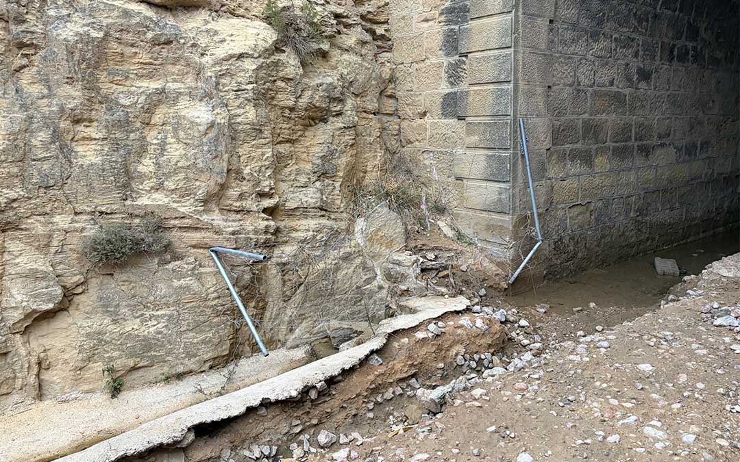 Piedras y agua en uno de los laterales en la entrada del túnel donde se aprecian los restos de valla arrancada por la riada. / B. Severino