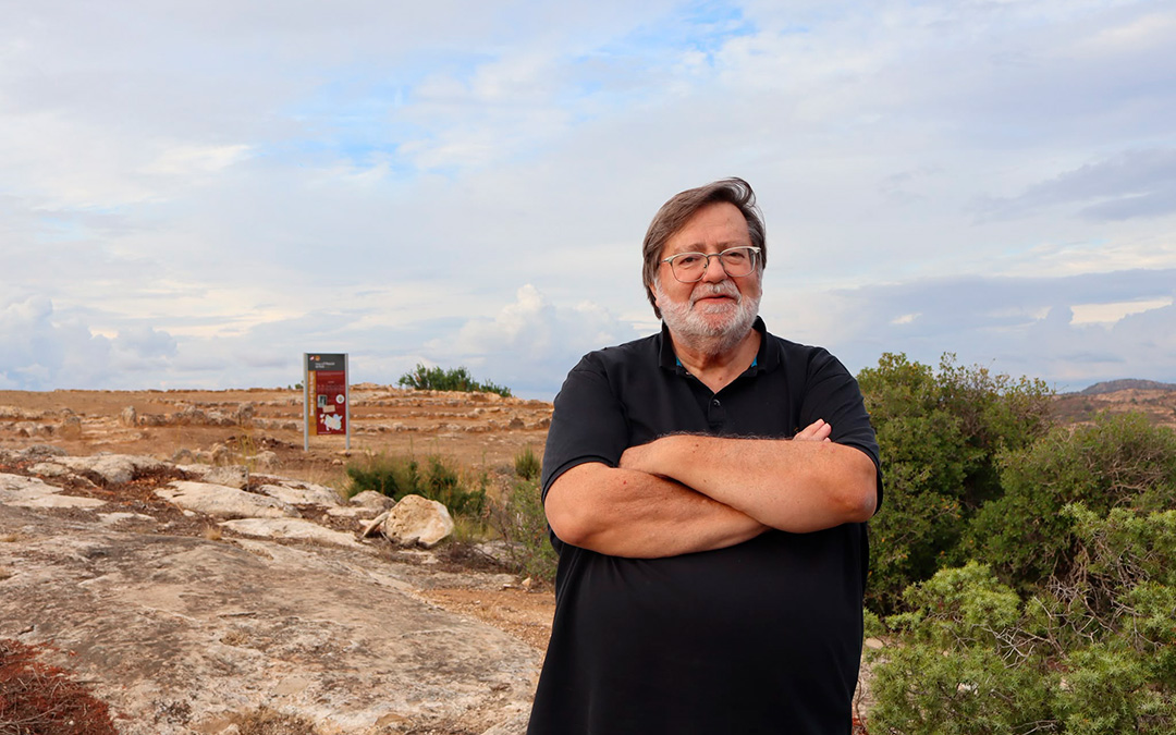 El catedrático en prehistoria en el Roquizal del Rullo de Fabara este sábado. Regresó tras más de 50 años y en el fondo puede verse uno de los carteles instalados, donde aparece su nombre. /Alba Zurita